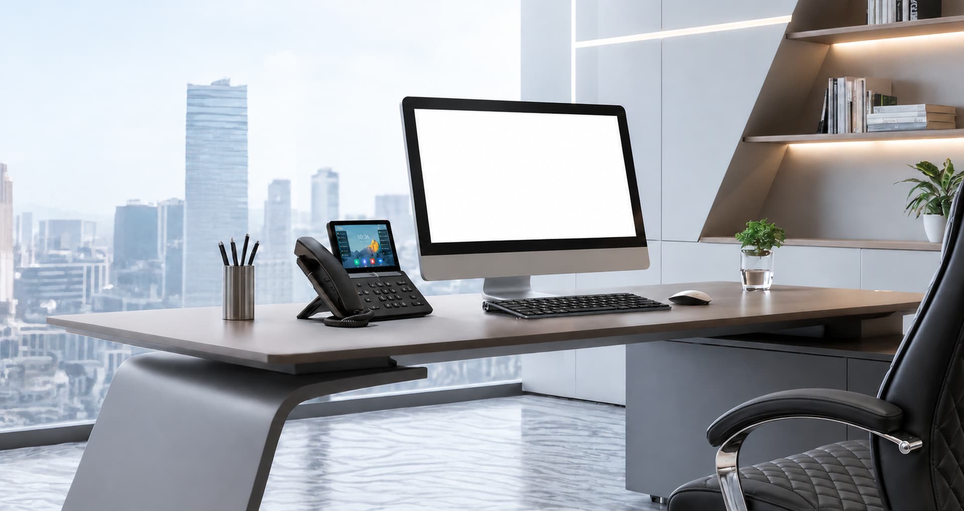 An office desk by a window over the city, with a desk phone, keyboard and a large monitor